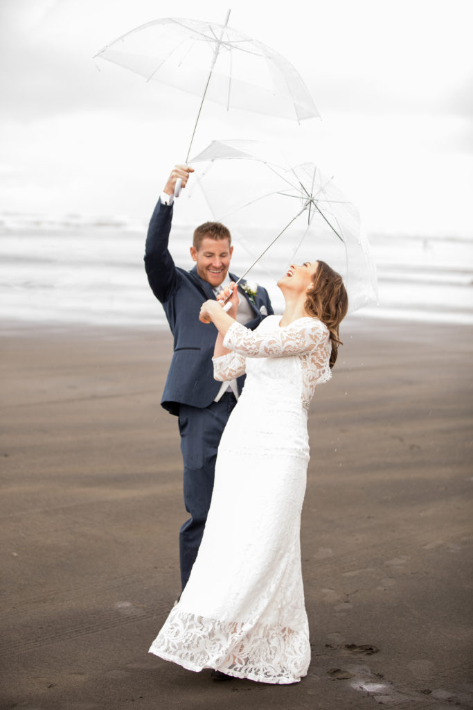 Beautiful couple plays in the rain under clear umbrellas.