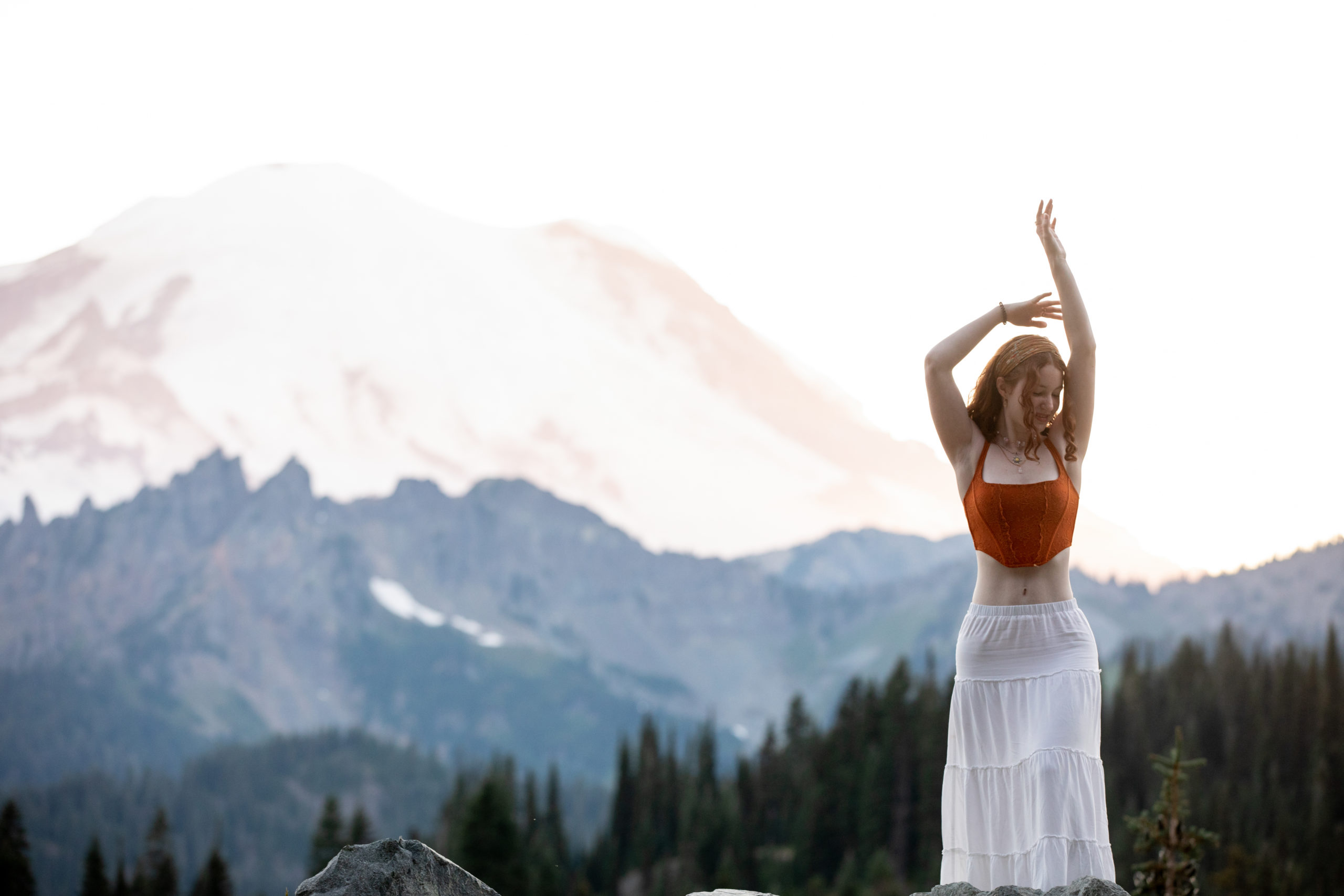 MOUNT RAINIER SENIOR PORTRAITS Lake Washington High School Class of 2023. Stands in Front of Mount Rainer in a white skirt, orange top and Dances with joy! 